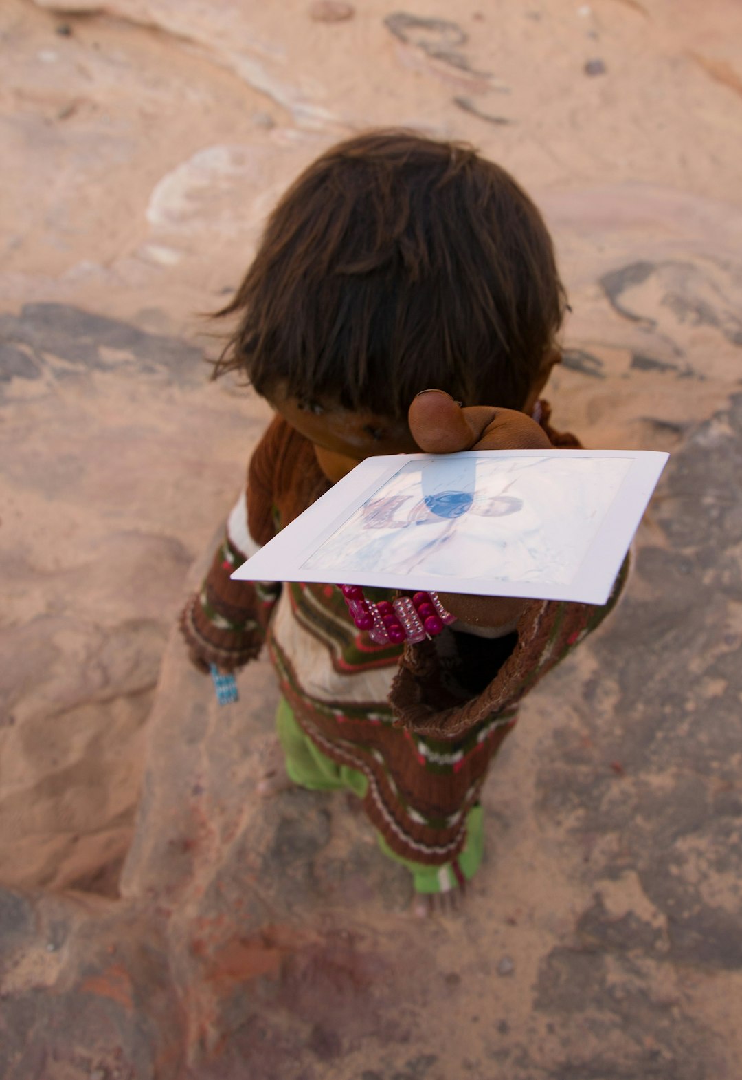 Boy holding a photo by Best Kids Tablets boy in brown shirt holding white printer paper